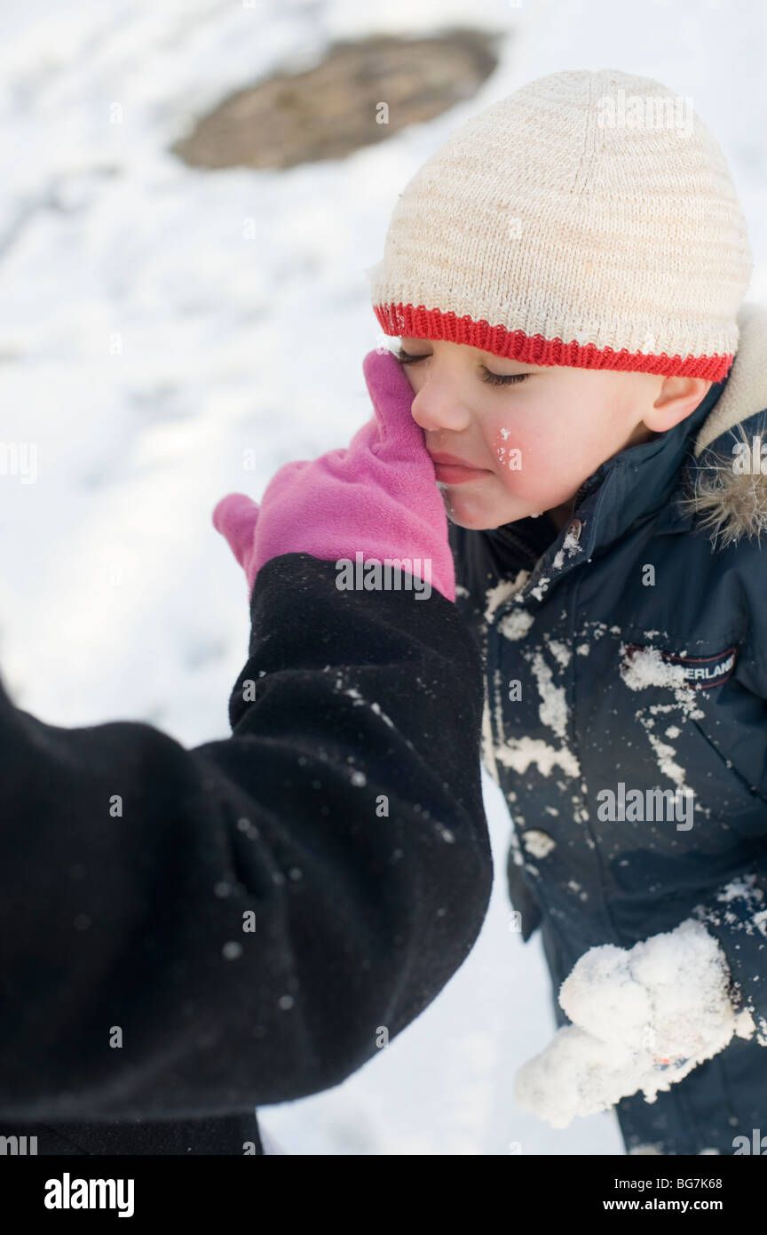 4 ans garçon hispanique joue dans la neige fraîchement tombée dans sa cour d'avec sa mère. Modèle droit est libéré. Banque D'Images