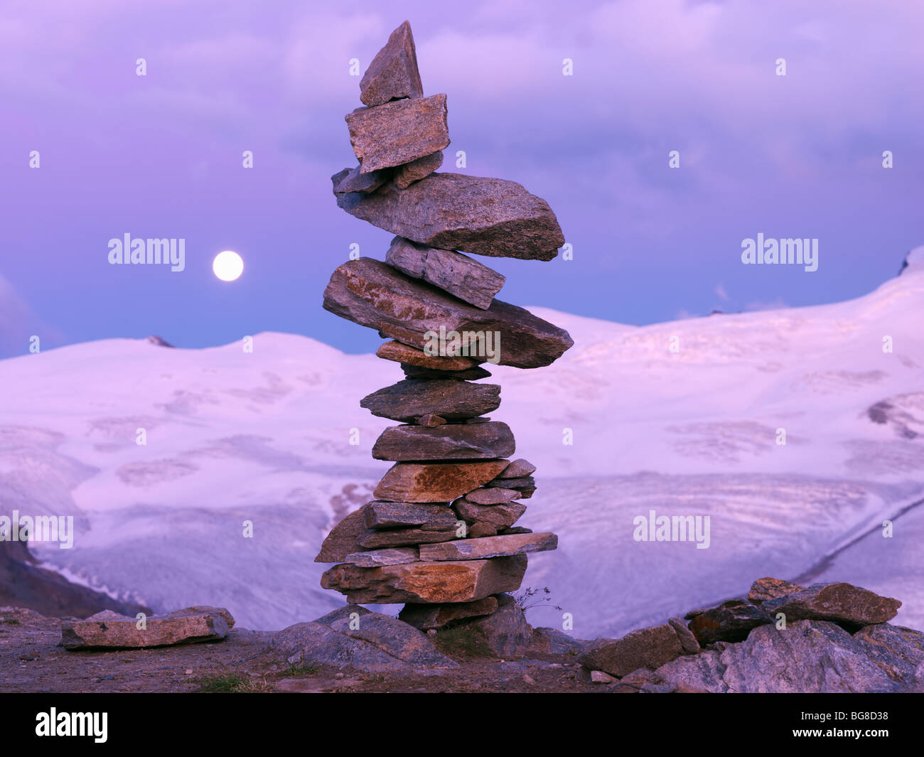 Suisse, Valais, Zermatt Gornergrat,,un cairn de pierres équilibré avec une montée de la lune et les montagnes en arrière-plan Banque D'Images