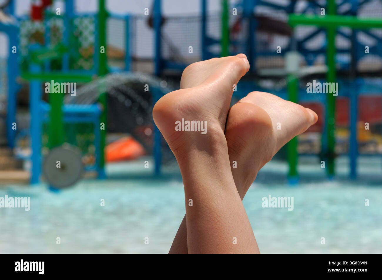 Les pieds nus du jeune femme de détente sur chaise longue près d'une  piscine dans un parc de l'eau Photo Stock - Alamy
