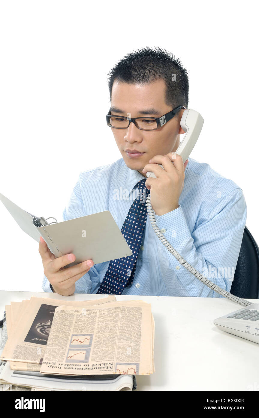 Businessman looking at un journal personnel et de parler sur un téléphone fixe Banque D'Images