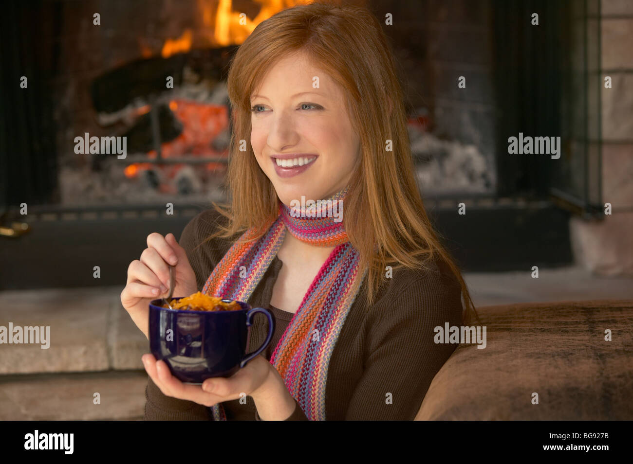 Girl eating chili sur un mug par un incendie Banque D'Images