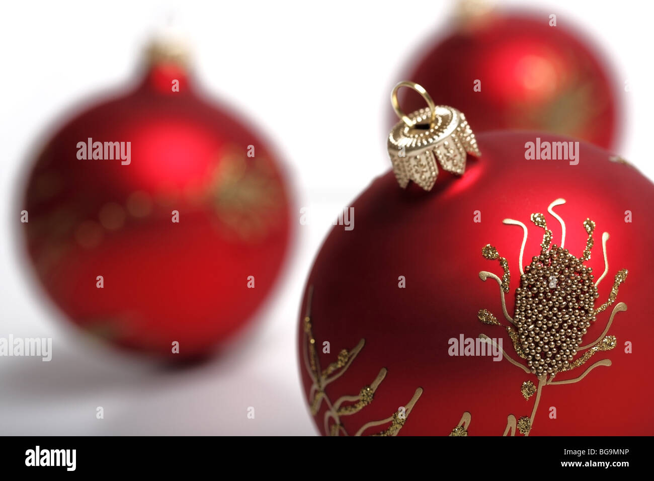 3 boules de décoration de Noël rouge sur un fond blanc. Se concentrer sur une balle de premier plan. Banque D'Images