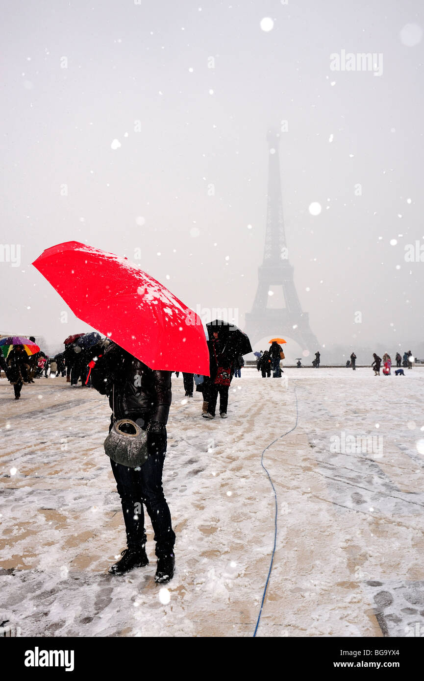 Paris, France, femme tenant un parapluie rouge en scène d'hiver, gens dans la tempête de neige, touristes se tenant près de la Tour Eiffel sur la sombre place Trocacacadéro Banque D'Images