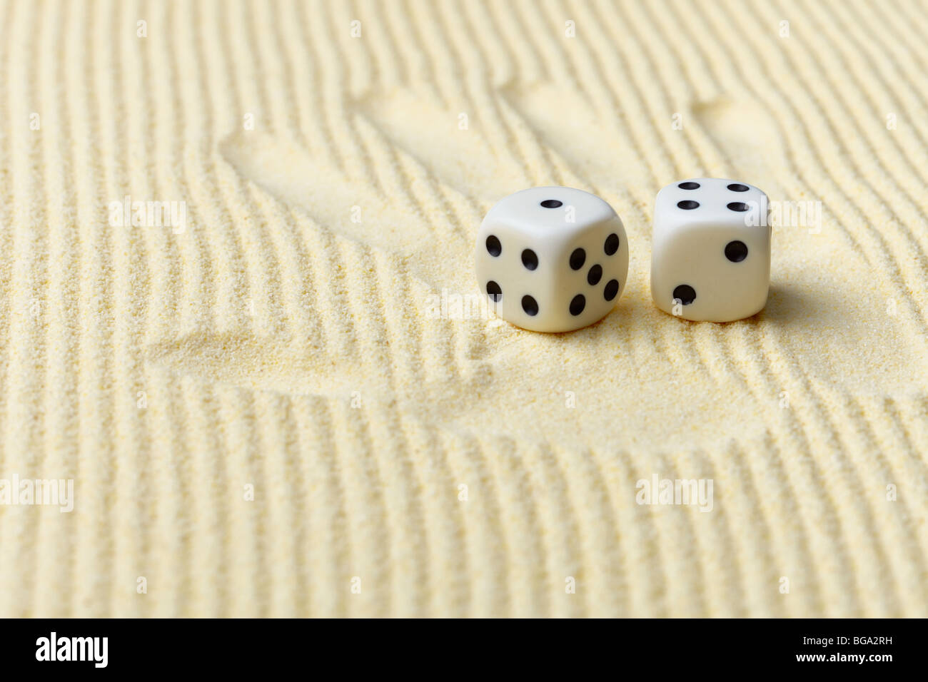 Dés sur une surface de sable et d'un palm print - un art abstrait composition dans des tons jaune Banque D'Images