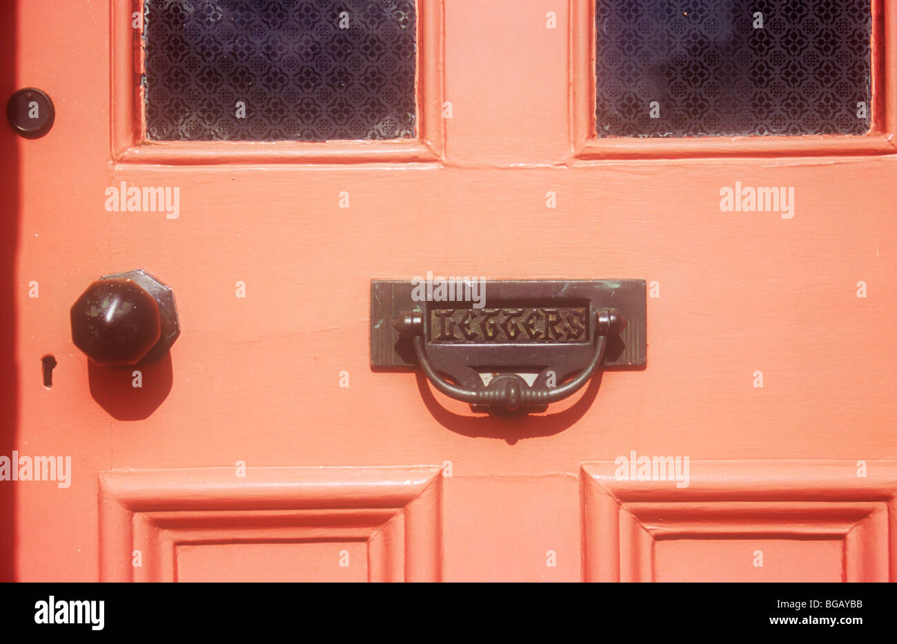 Edwardian porte peint en orange, mais la décoloration avec verre dépoli et panneaux massifs de bois poignées et gothique et knocker letterbox Banque D'Images