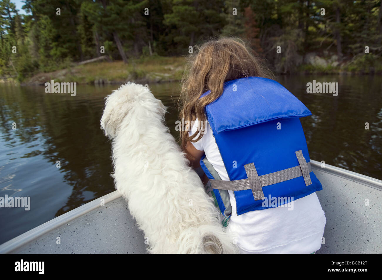 Petite fille avec petit chien blanc en bateau ; le lac des Bois, Lulu, Ontario, Canada Banque D'Images