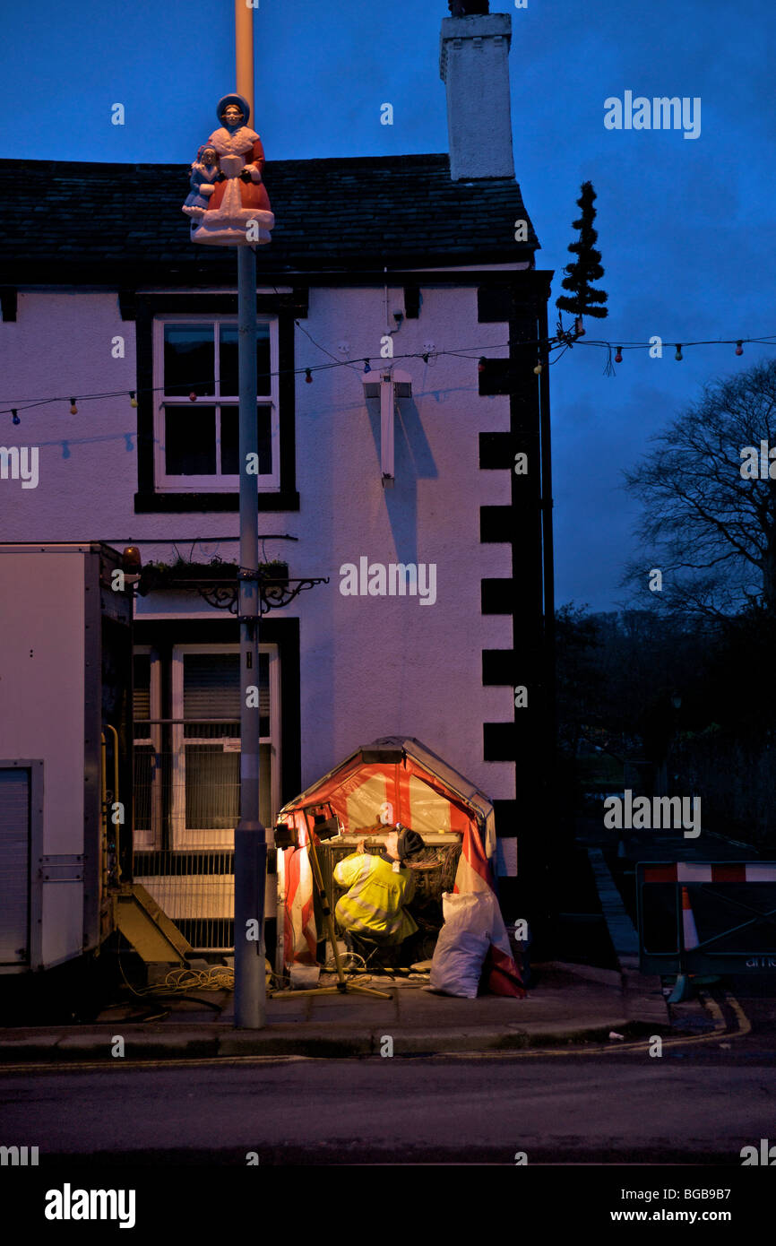 Ingénieur des télécommunications (Openreach) jette un coup d'œil à la décoration de Noël sur la rue de la Couronne, Cockermouth, après les inondations Banque D'Images