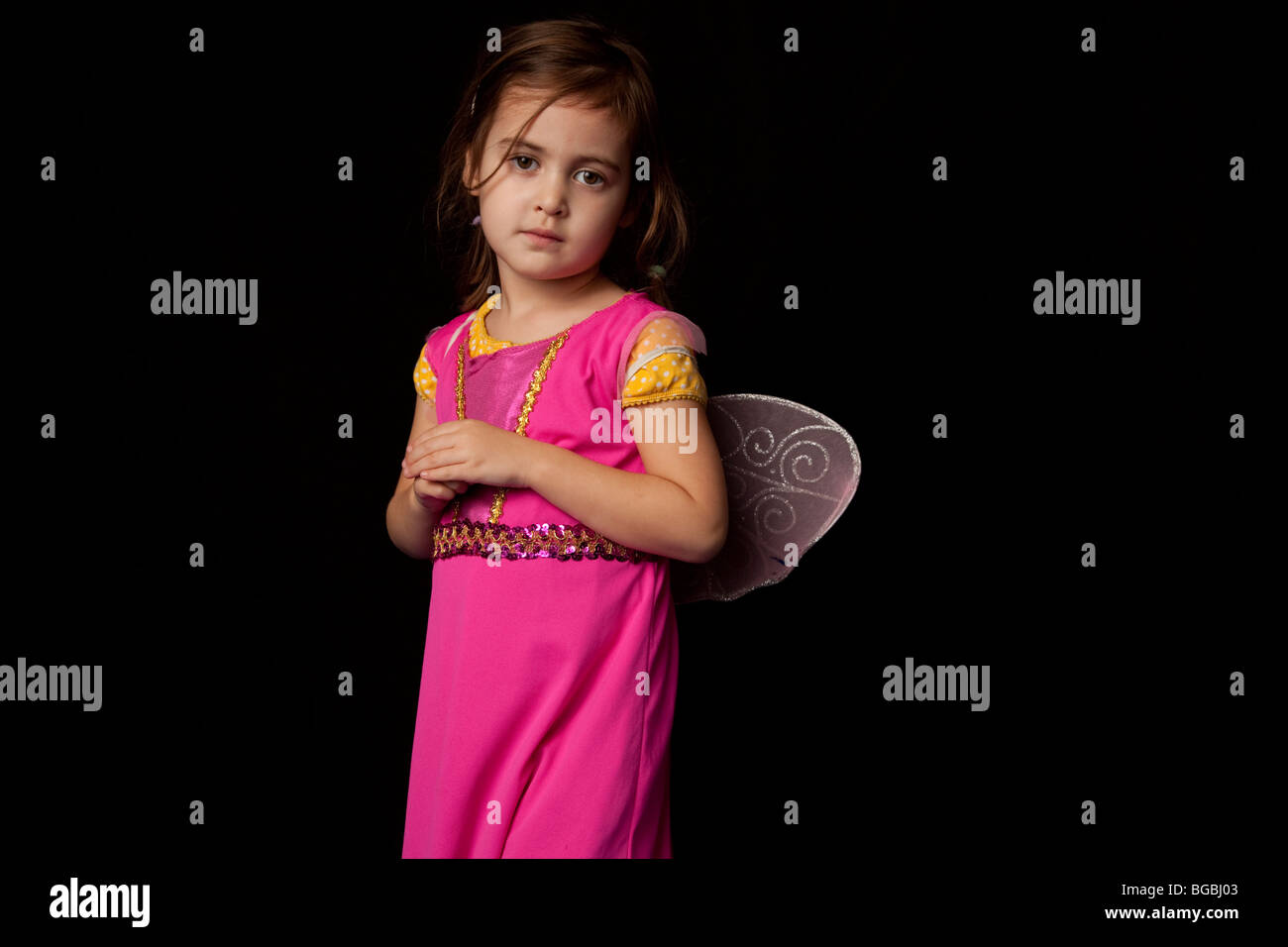 4 ans, fille avec robe rose et des ailes sur fond noir Banque D'Images