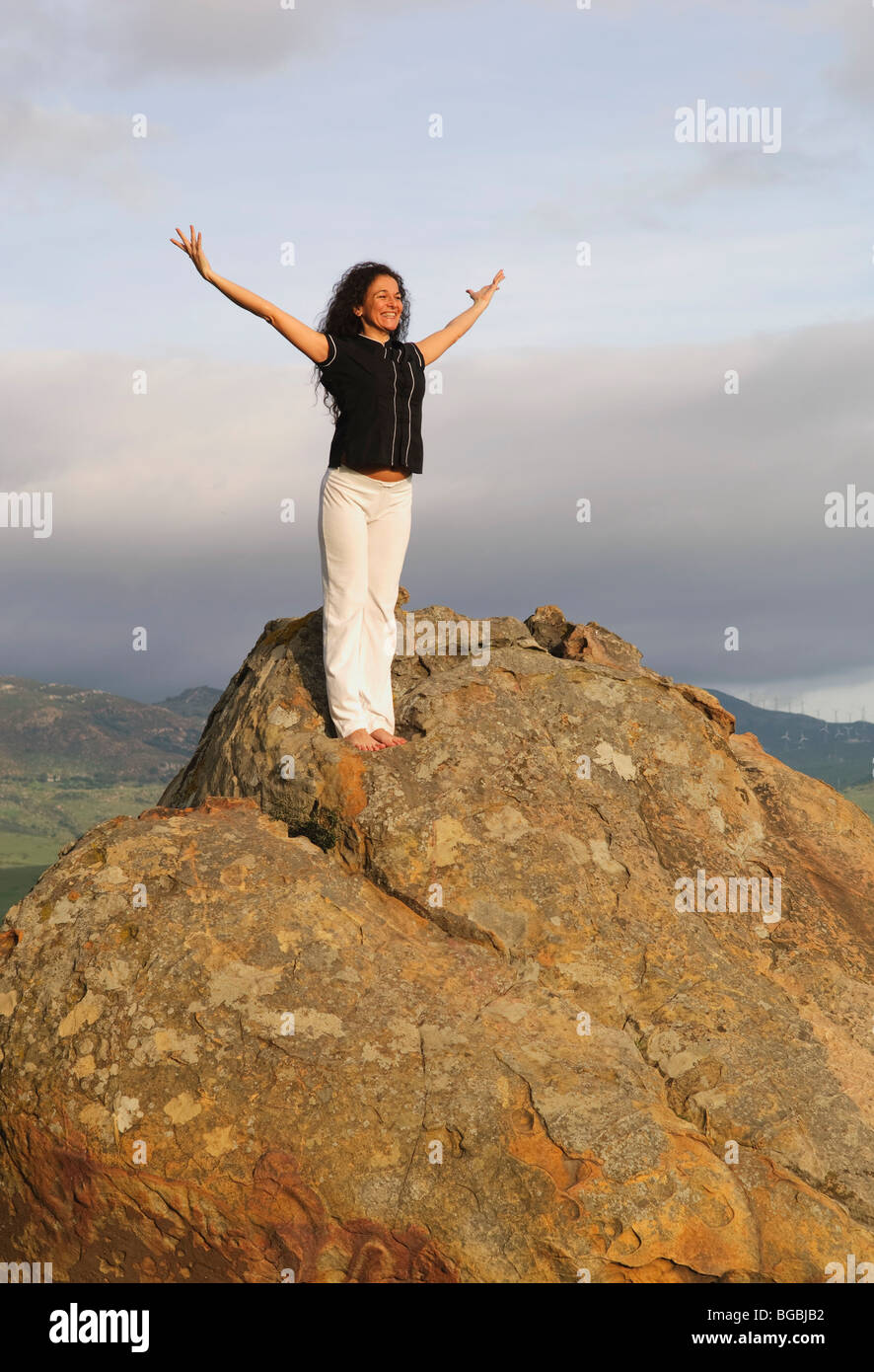 Woman on mountain peak with arms raised Banque D'Images