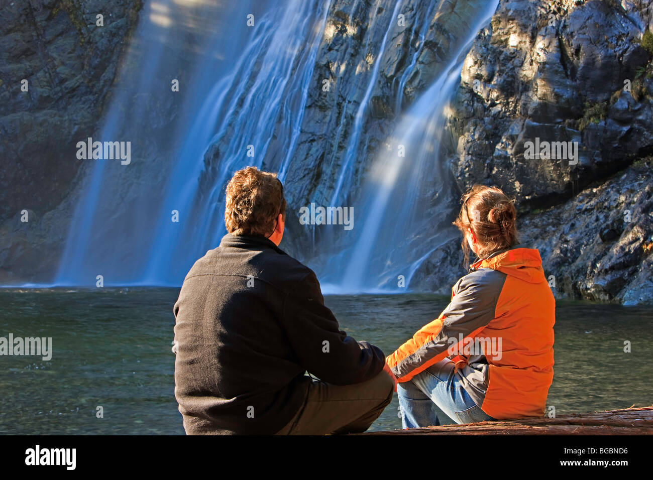 Couple sitting on a log affichage de la Virgin Falls qui plongent 53 mètres/174 pieds en éventail sur une formation escarpement rocheux le long Banque D'Images