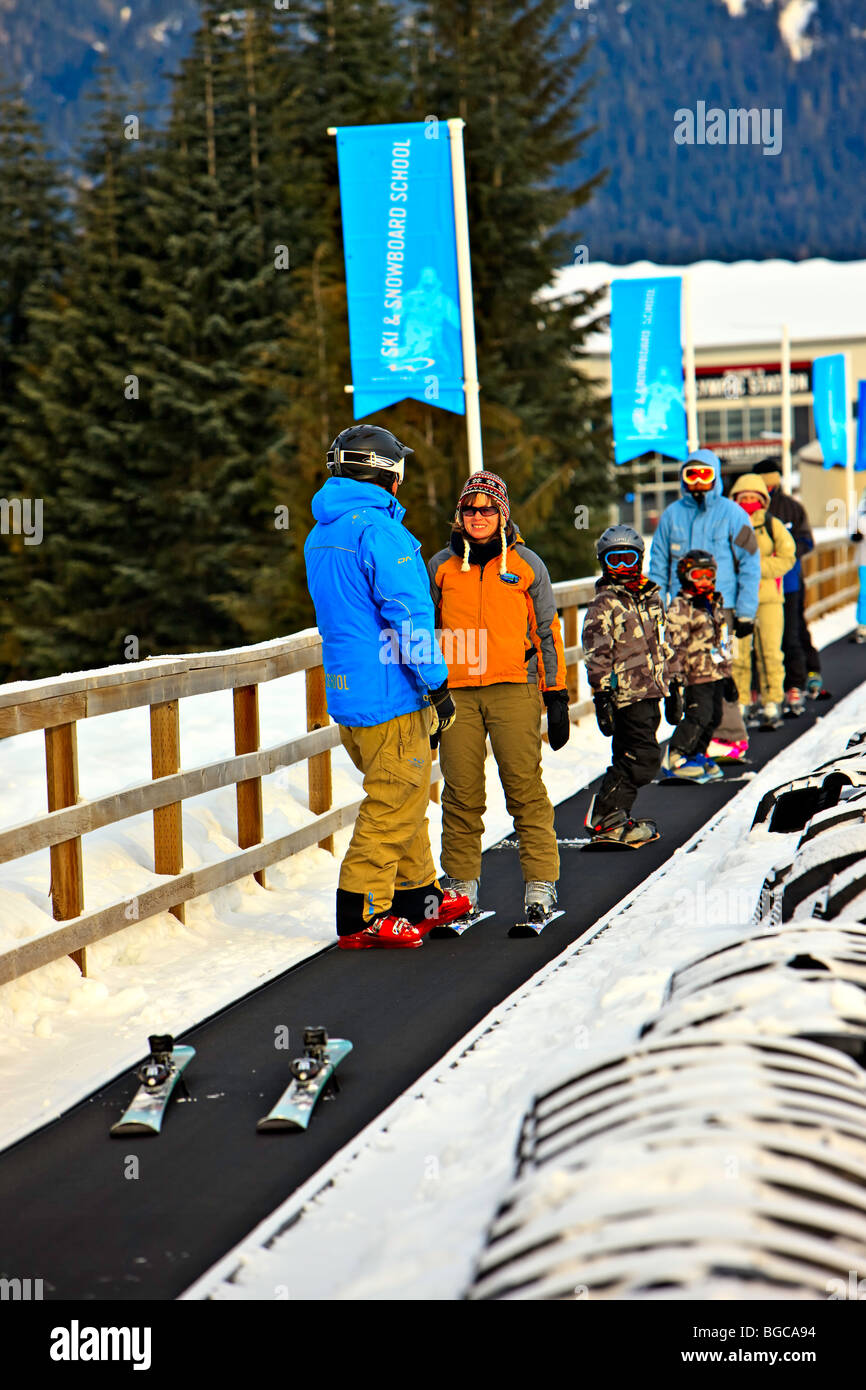 Moniteur de ski et étudiant sur le tapis magique de la pente de débutants mont Whistler, Whistler Blackcomb, Whistler, B Banque D'Images