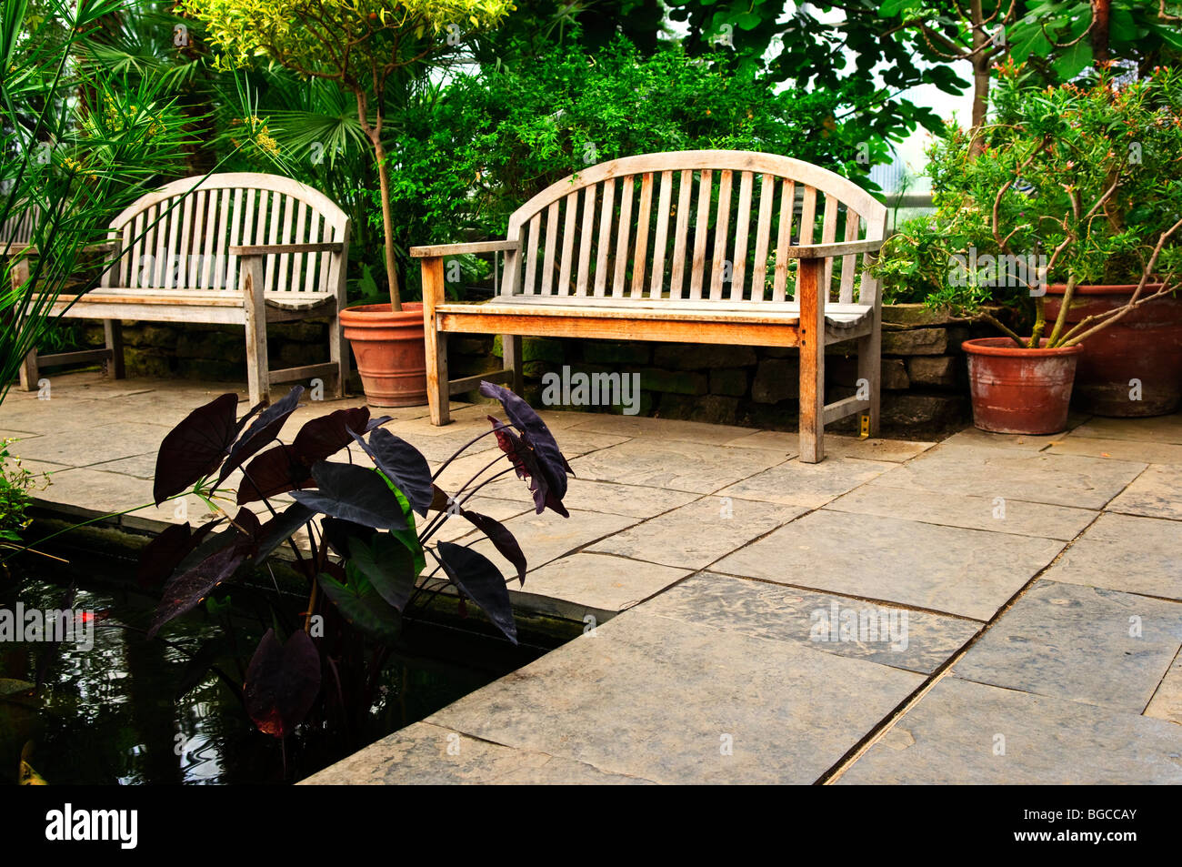 Jardin verdoyant avec Stone Landscaping, étang et bancs Banque D'Images
