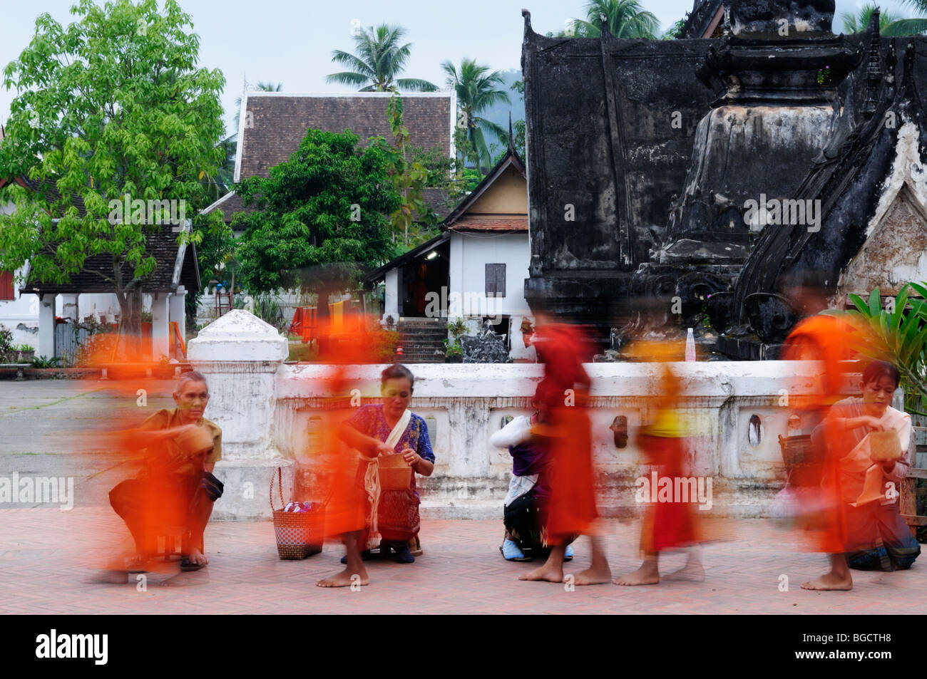 Le Laos, Luang Prabang ; une longue exposition de droit de moines recueillir des aumônes à l'aube Banque D'Images
