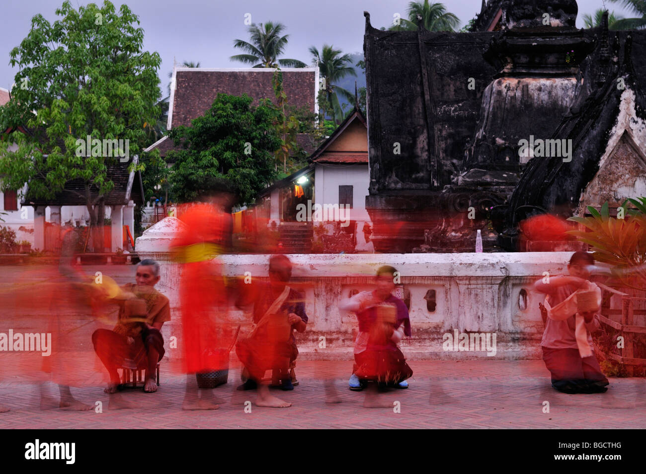 Le Laos, Luang Prabang ; une longue exposition de droit de moines recueillir des aumônes à l'aube Banque D'Images