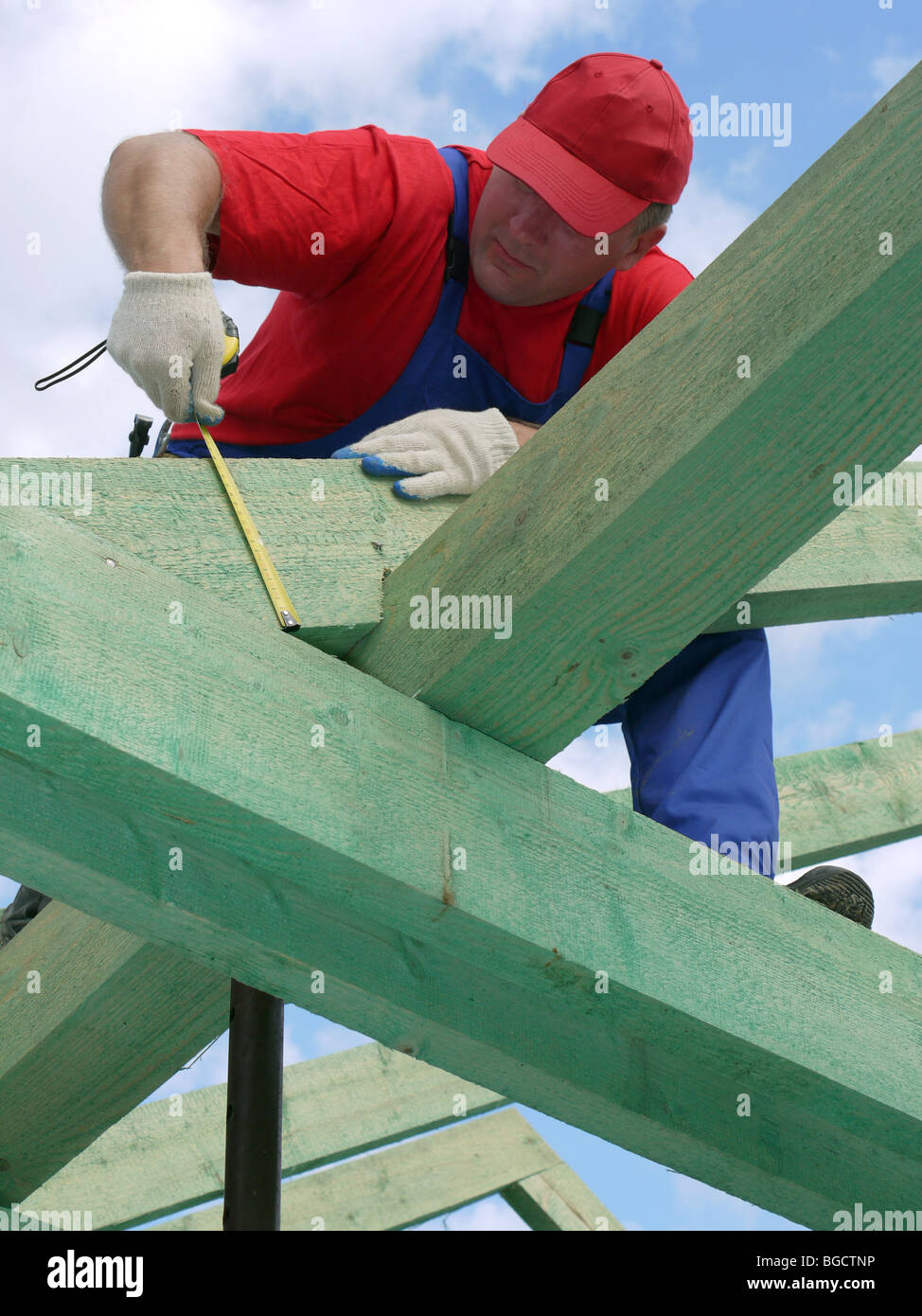 Carpenter en tenant la mesure de faisceaux de chevrons maison Banque D'Images