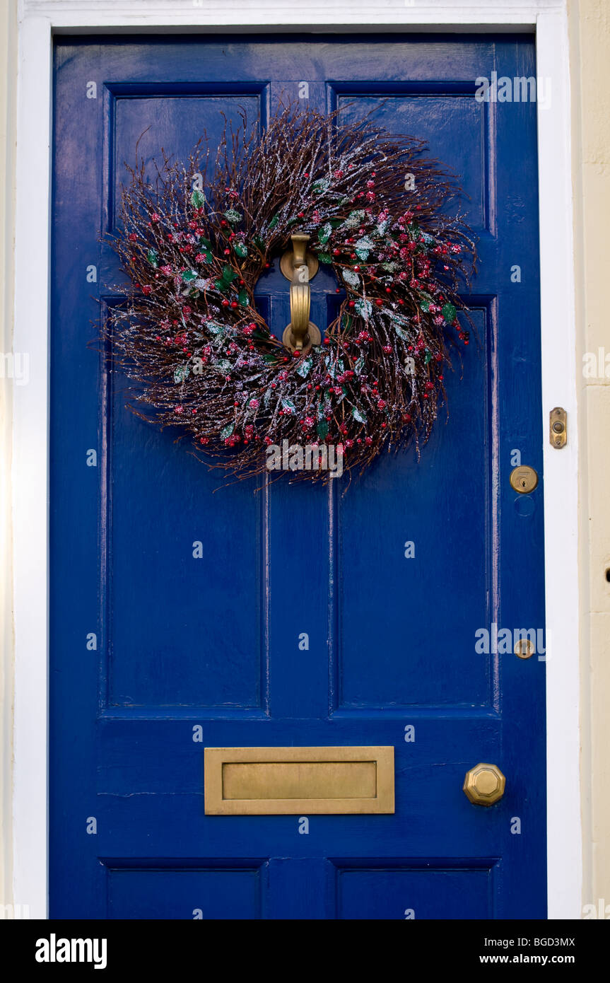 Couronne de Noël en bois peint bleu sur une porte d'une maison de ville traditionnelle anglaise. Banque D'Images