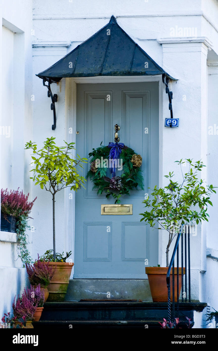 Regency traditionnel porte avec porche décoré de couronne de Noël et plantations autour de. Une maison de ville dans la région des Cotswolds. Banque D'Images