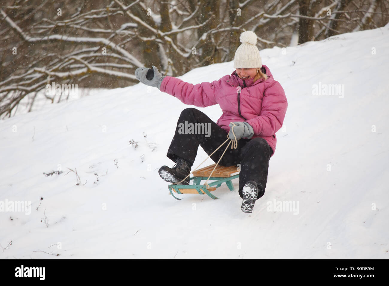 Fille de la luge en bas de la colline, lumineuse et joyeuse scène d'hiver Banque D'Images