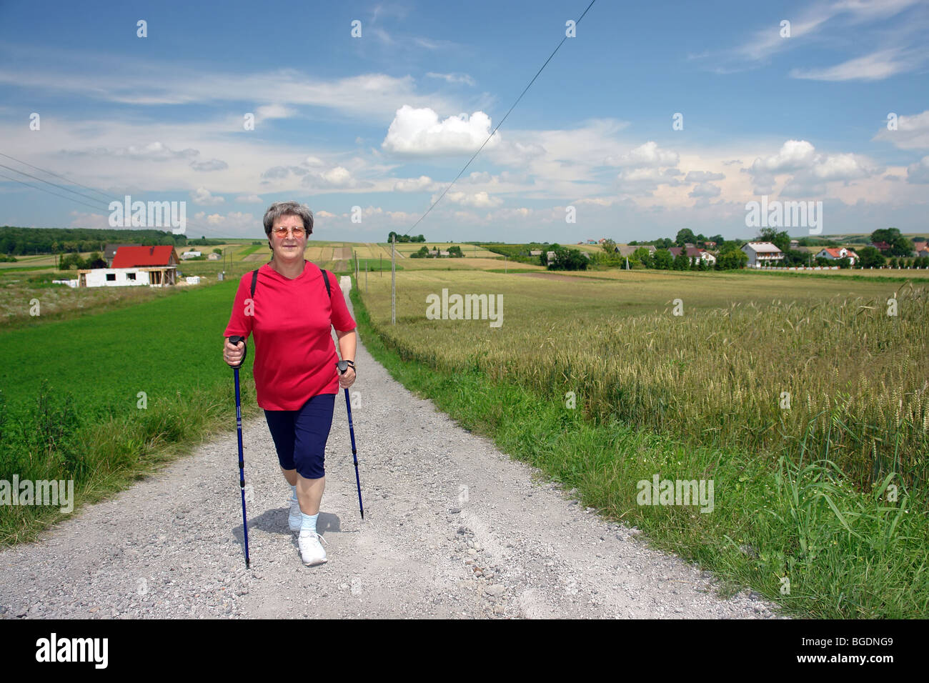 Senior woman pratiquer la marche nordique dans la campagne Banque D'Images