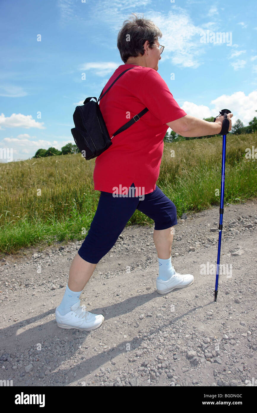 Senior woman pratiquer la marche nordique dans la campagne Banque D'Images