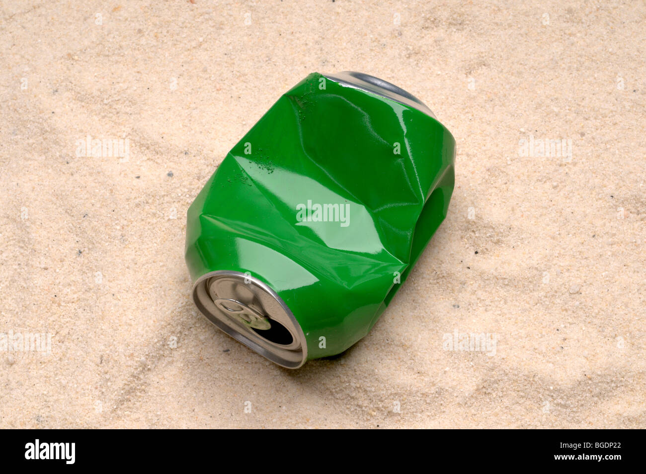 Une boîte en fer blanc vert jeté trash sur une plage de sable Banque D'Images