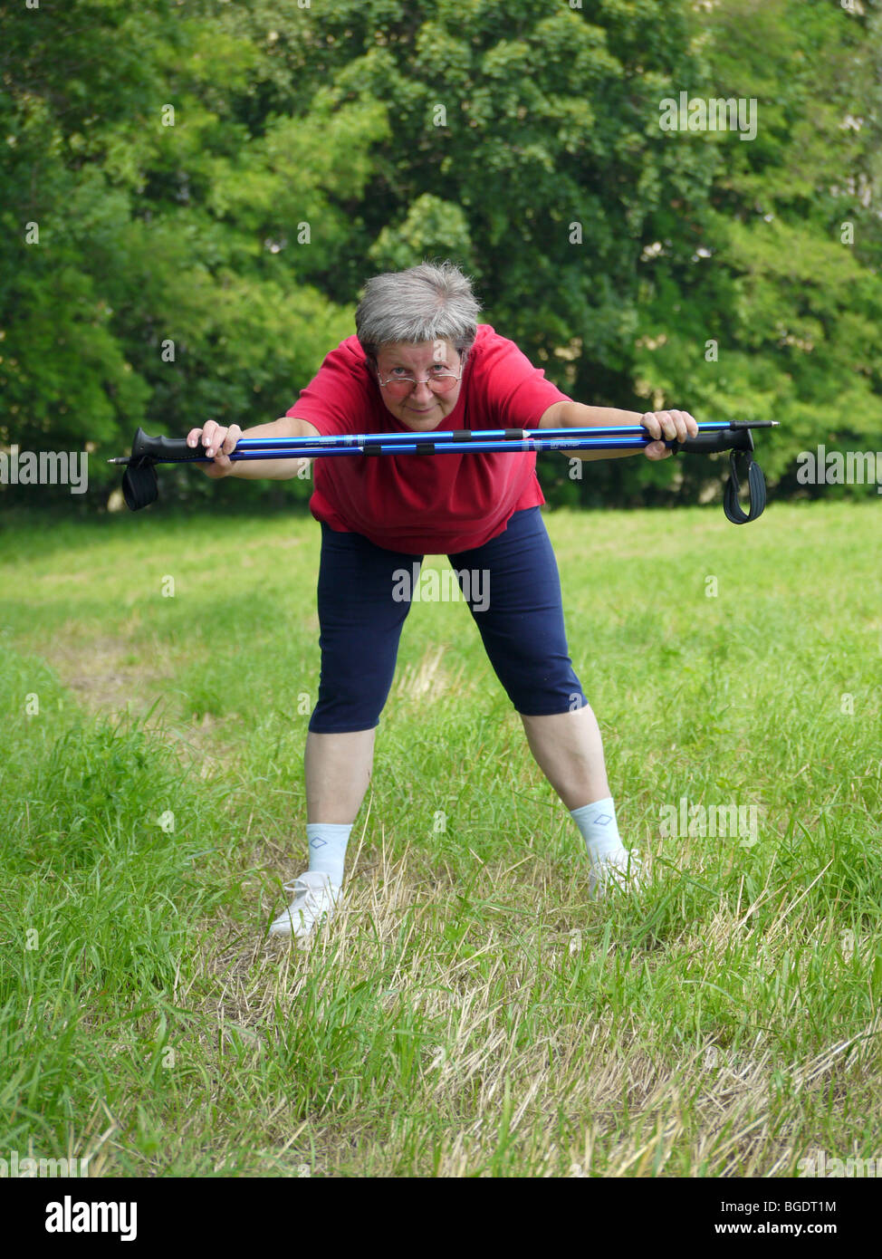 Senior woman doing une série d'exercices de réchauffement avec des bâtons de randonnée Banque D'Images