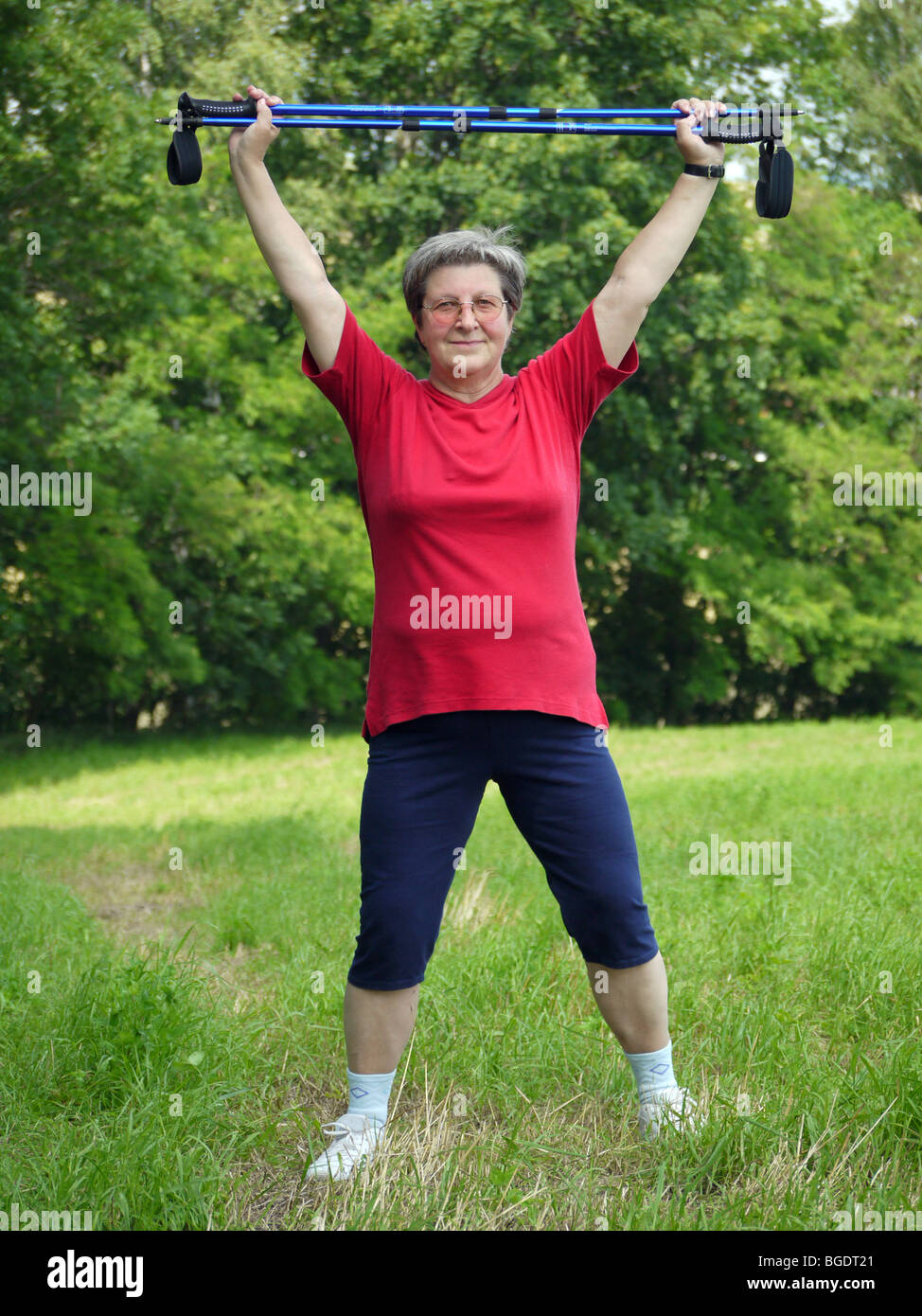 Senior woman doing une série d'exercices de réchauffement avec des bâtons de randonnée Banque D'Images