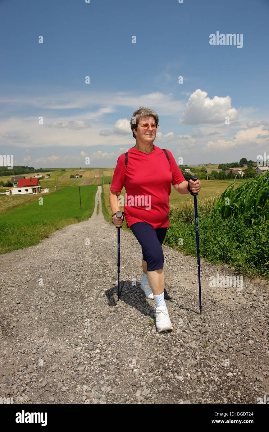 Senior woman pratiquer la marche nordique dans la campagne Banque D'Images