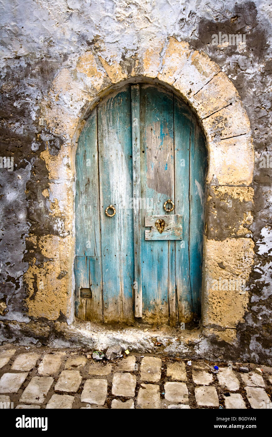 Ancienne porte voûtée dans un mur d'une cour pavée en Tunisie Banque D'Images