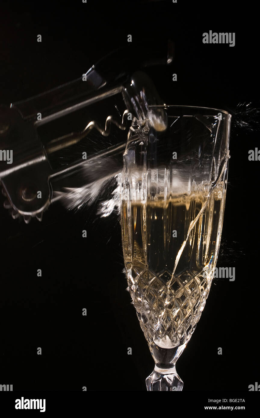 image igh-speed d'un verre à champagne qui se brise alors qu'un tire-bouchon le frappe sur un fond noir. Banque D'Images