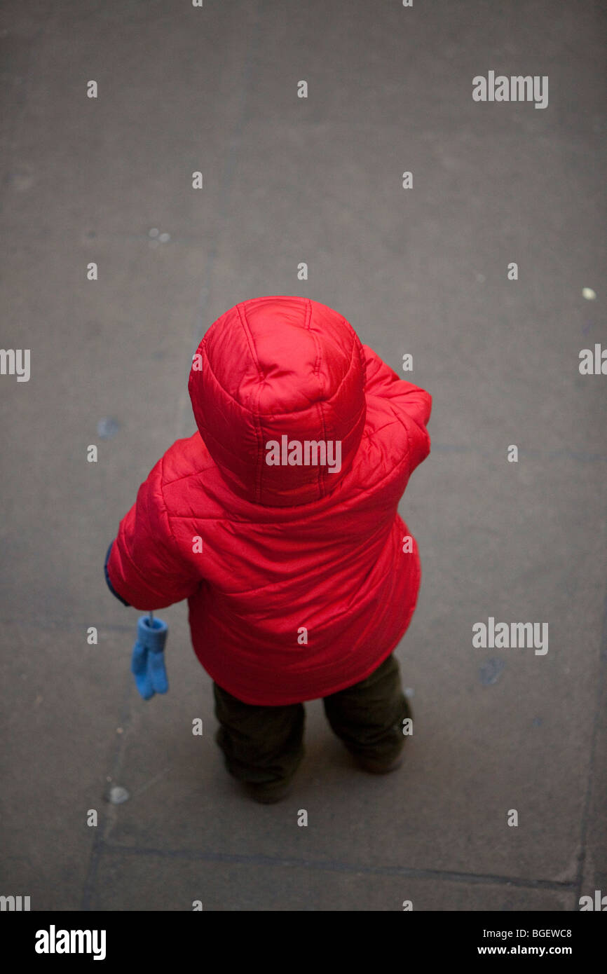 Vue arrière pleine longueur portrait d'un petit enfant perdu portant un sweat rouge, London, England, UK Banque D'Images