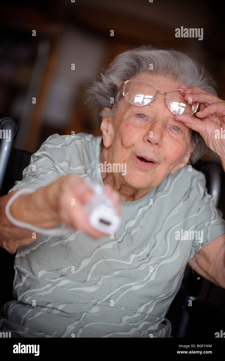 Une retraité lève ses lunettes tout en jouant à la Nintendo Wii. Banque D'Images