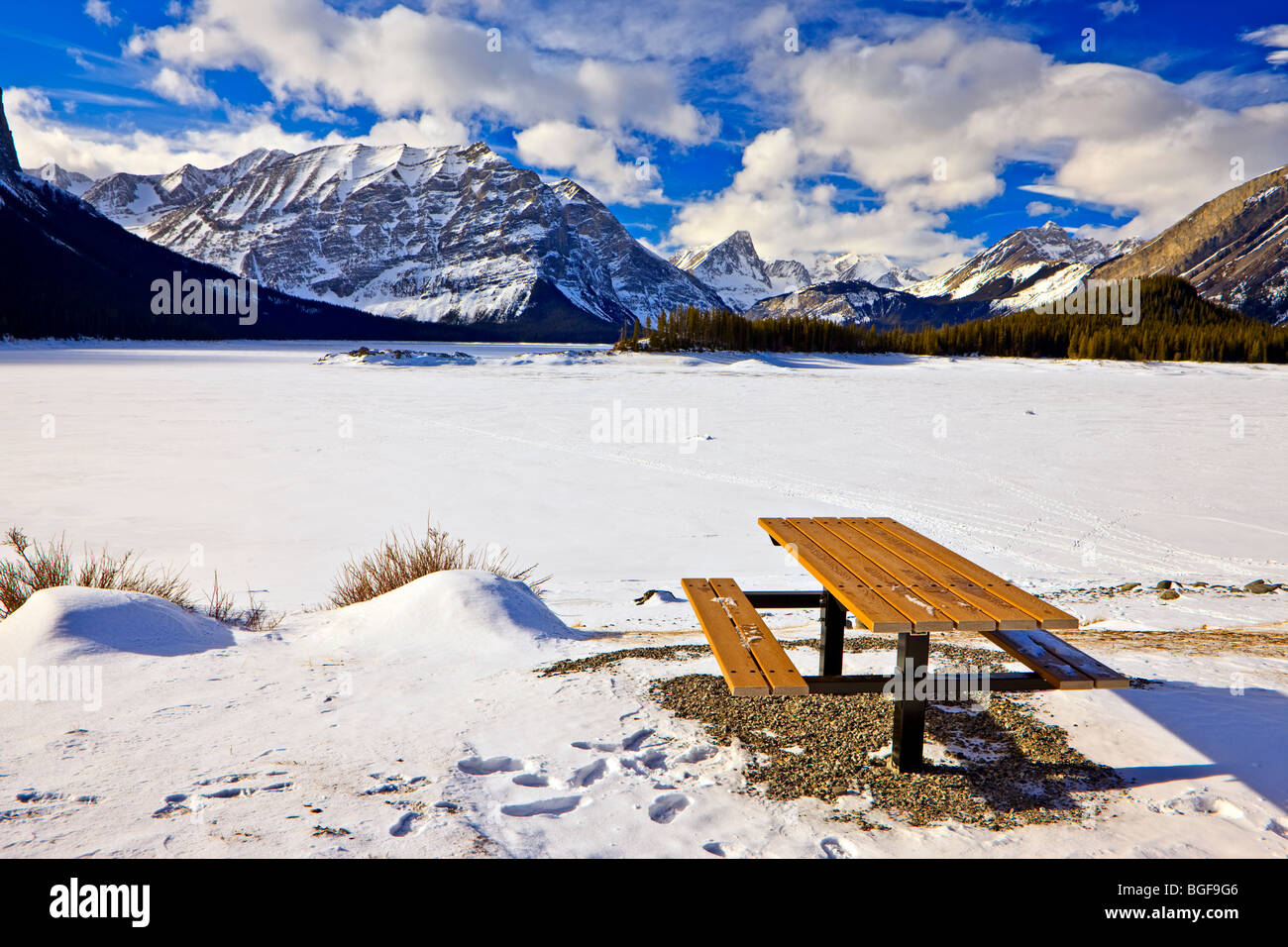 Table de pique-nique sur les rives d'une gelé et recouvert de neige Lac Kananaskis supérieur au cours de l'hiver, backdropped par la gamme de Kananaskis Banque D'Images