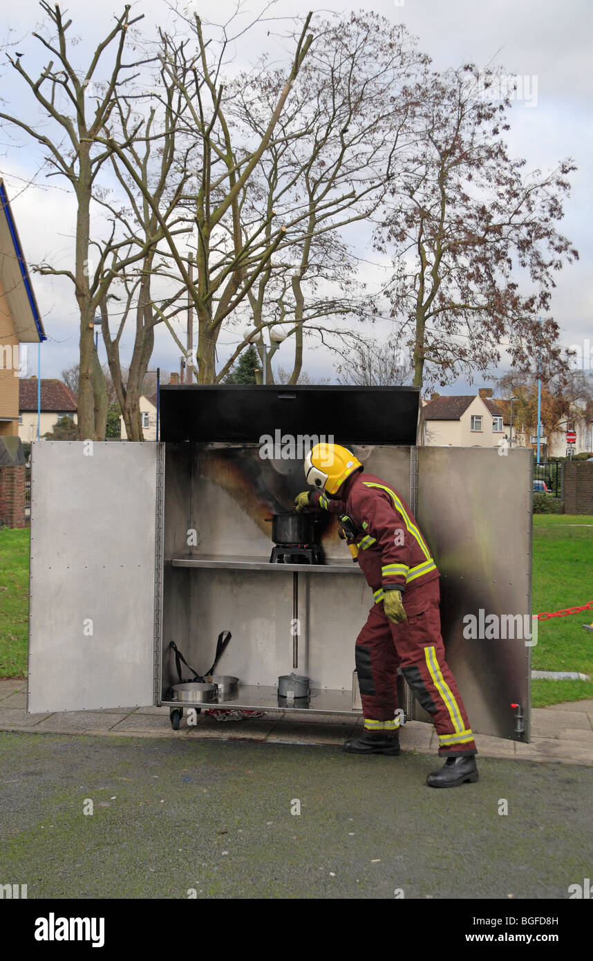 Un London Fire Brigade pompier vérifie une huile en feu rempli avant un pan de démonstration de la sécurité-incendie en décembre 2009. Banque D'Images