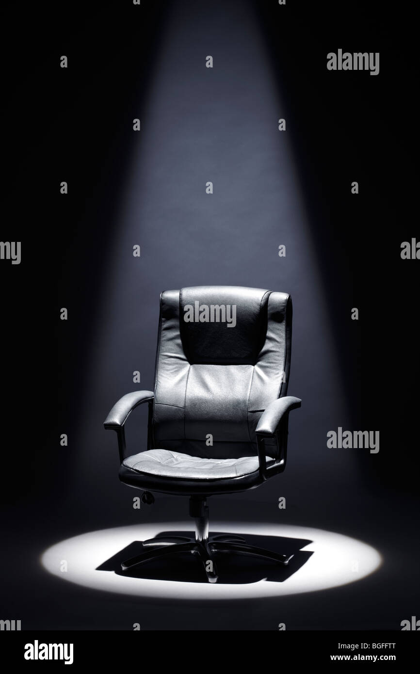 Fauteuil en cuir noir vide sous Spotlight Mastermind Banque D'Images
