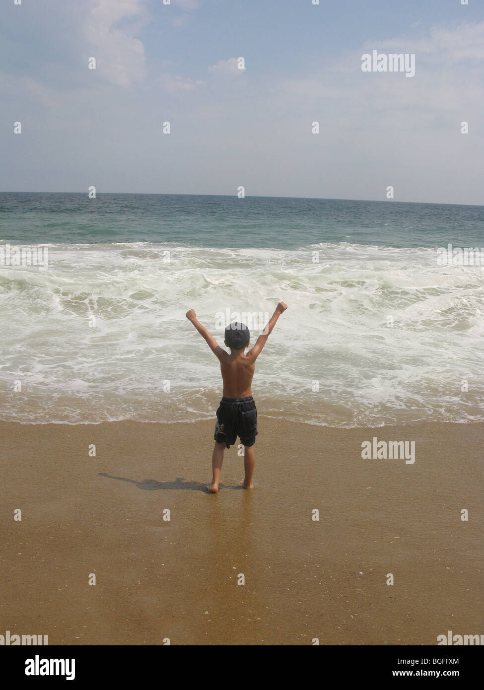 Un jeune garçon au bord de l'eau plage vagues Banque D'Images