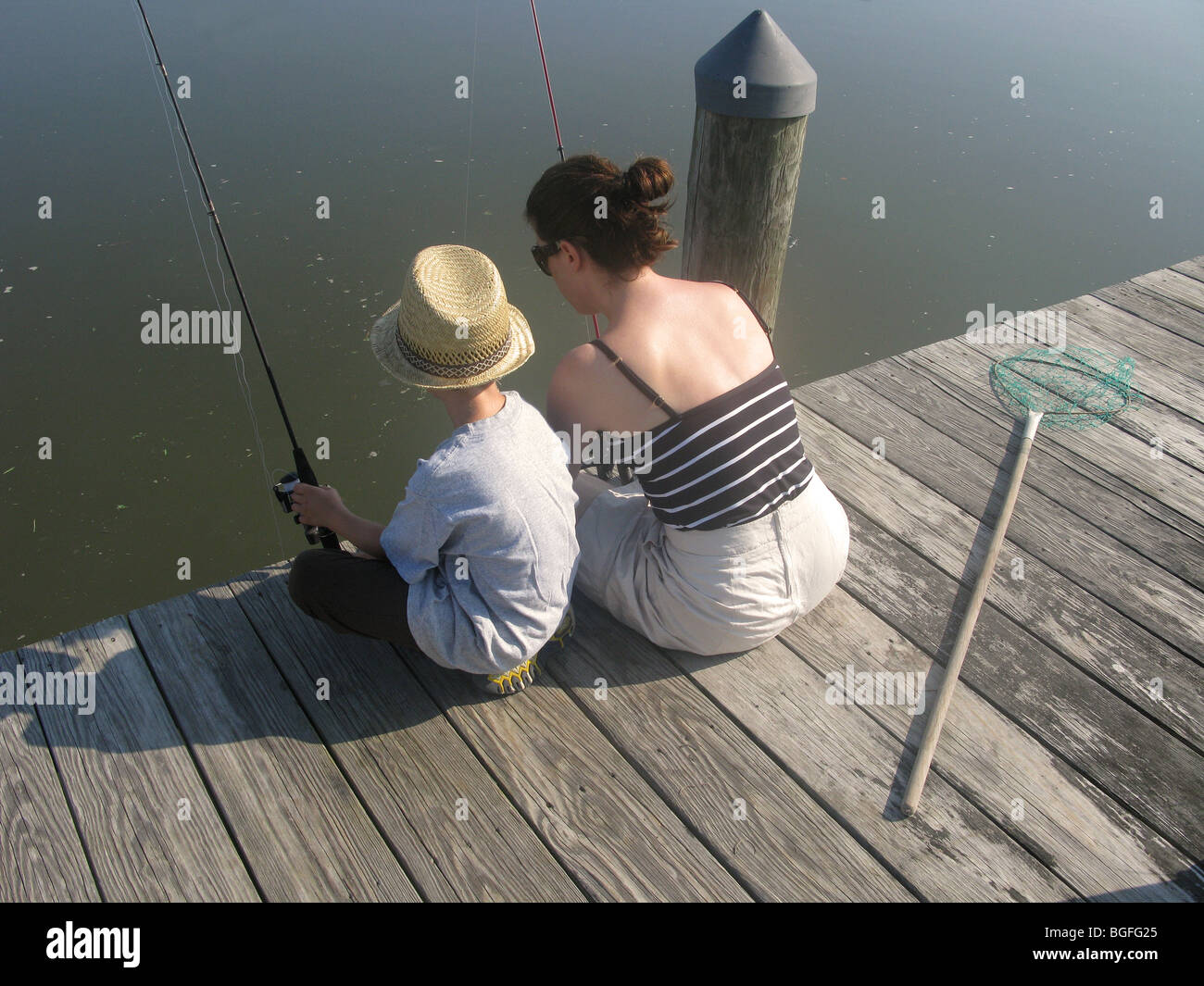 Une mère et son fils assis sur un quai en bois pêche à la ligne Banque D'Images
