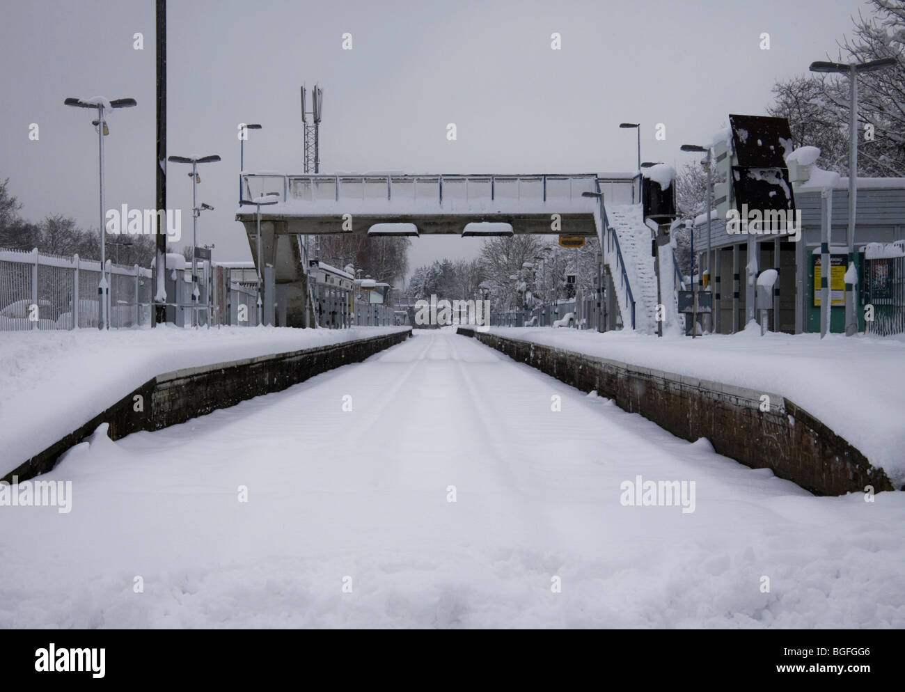 Ashtead gare à Surrey vu depuis le passage à niveau, le long de la ligne de chemin de fer qui est bloqué par la neige Banque D'Images