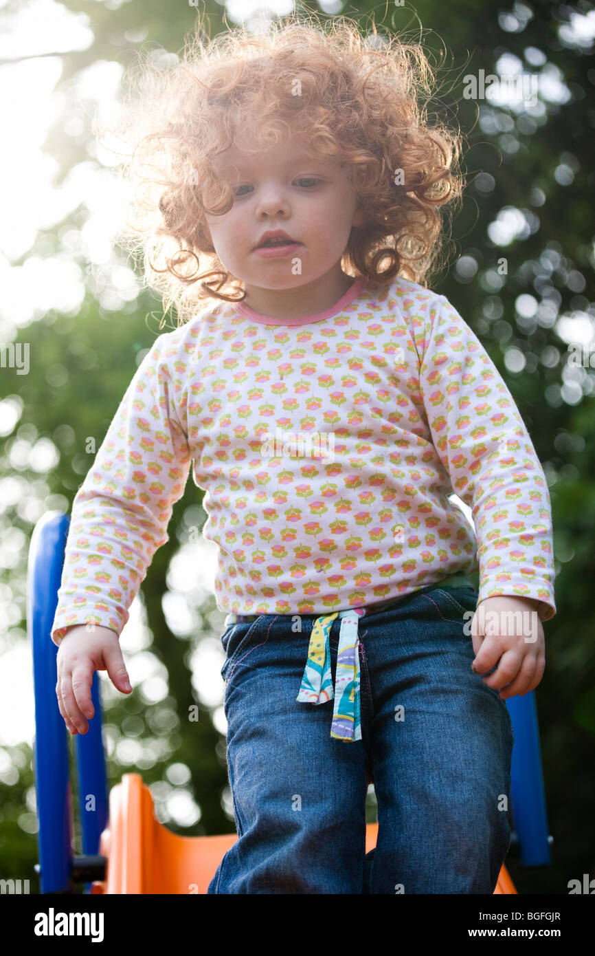 Une fillette de deux ans sur une diapositive dans un jardin Banque D'Images