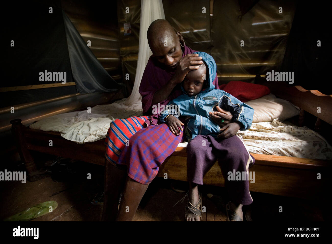 Un homme de maasai du Kenya, Rombo console son enfant malade à la lumière des ONG en Afrique. La région de Kilimandjaro, Tanzanie. Banque D'Images