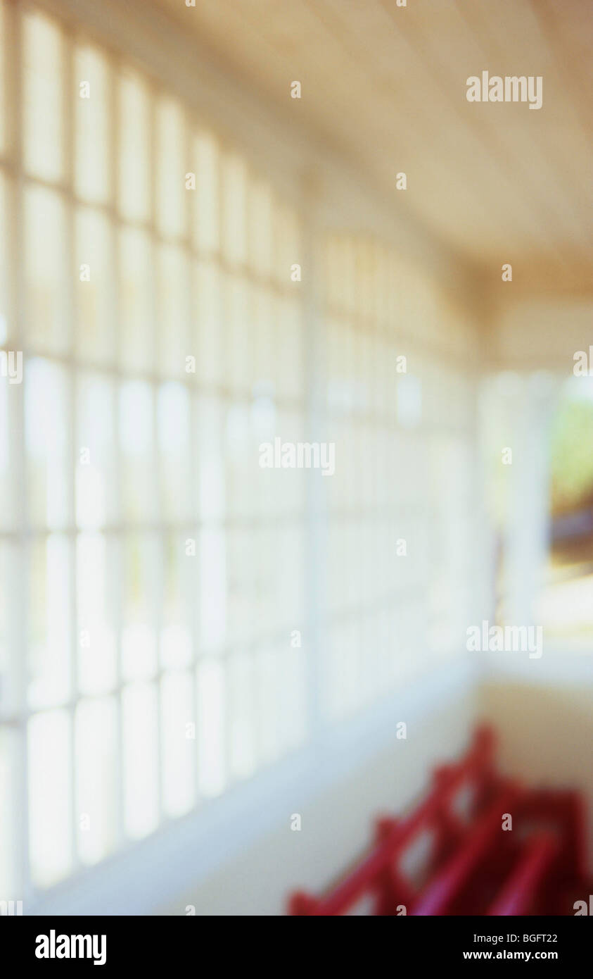 Blanc crème et d'impressions, à l'abri dans une lumière chaude avec banc peint en rouge à l'intérieur et beaucoup de petits carreaux de verre Banque D'Images