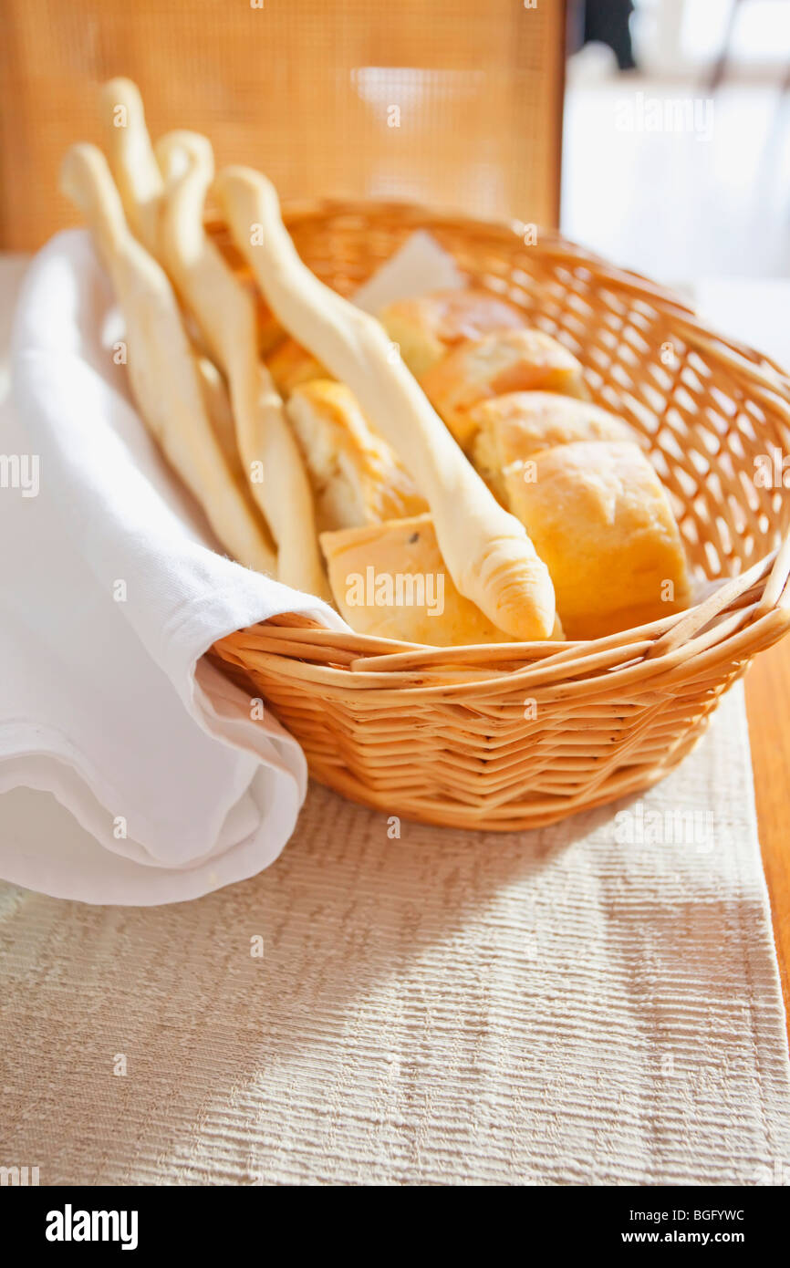 Une variété de pains italiens frais dans un panier en osier, drapé d'un linge de lin blanc. Banque D'Images