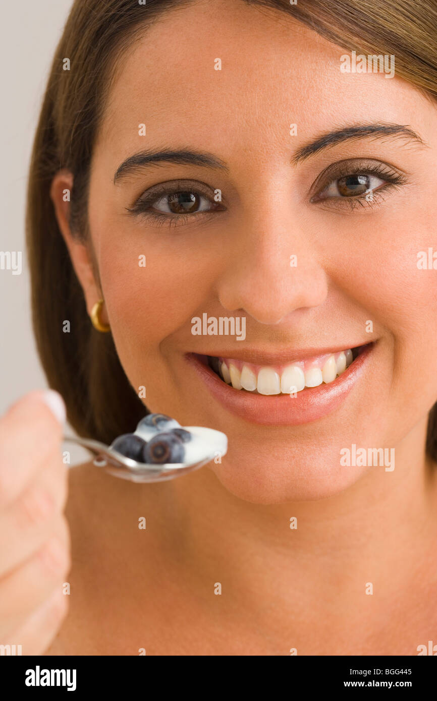 Femme mangeant un yaourt au bleuet, smiling, portrait, Close up Banque D'Images