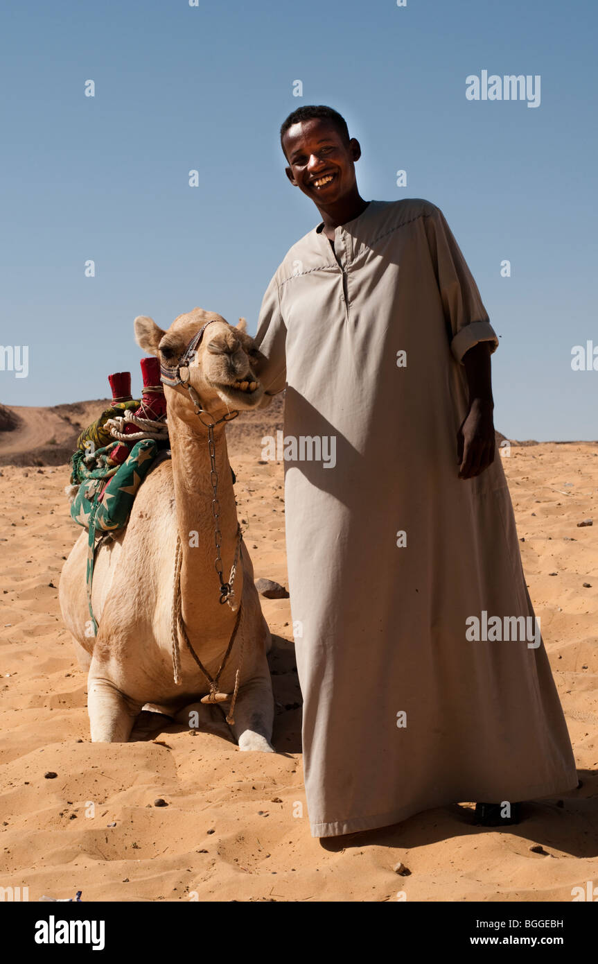 Les jeunes nubien vêtu mène son chameau à travers le désert du Sahara. Banque D'Images