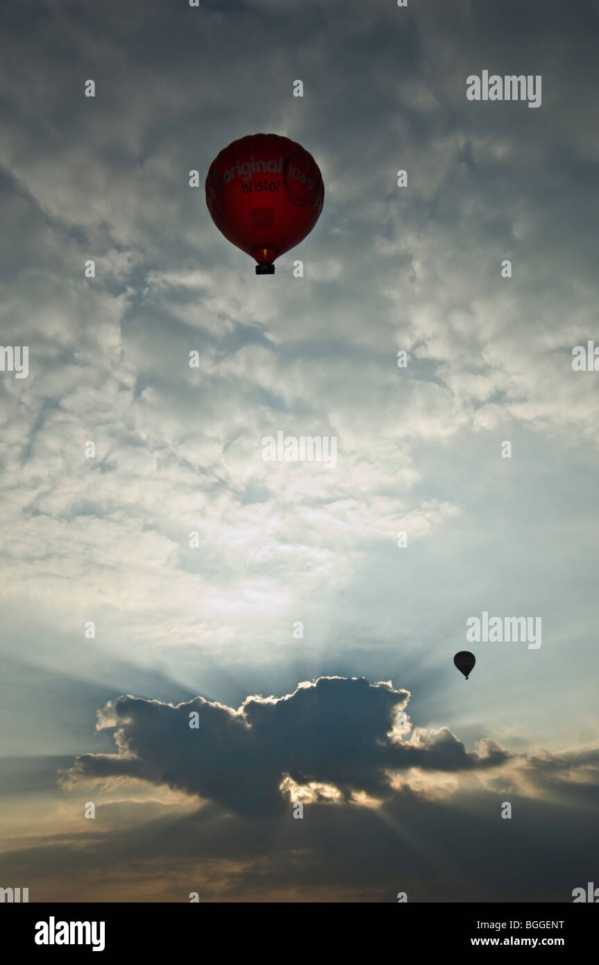 Balloons flying in sky avec soleil derrière les nuages Banque D'Images