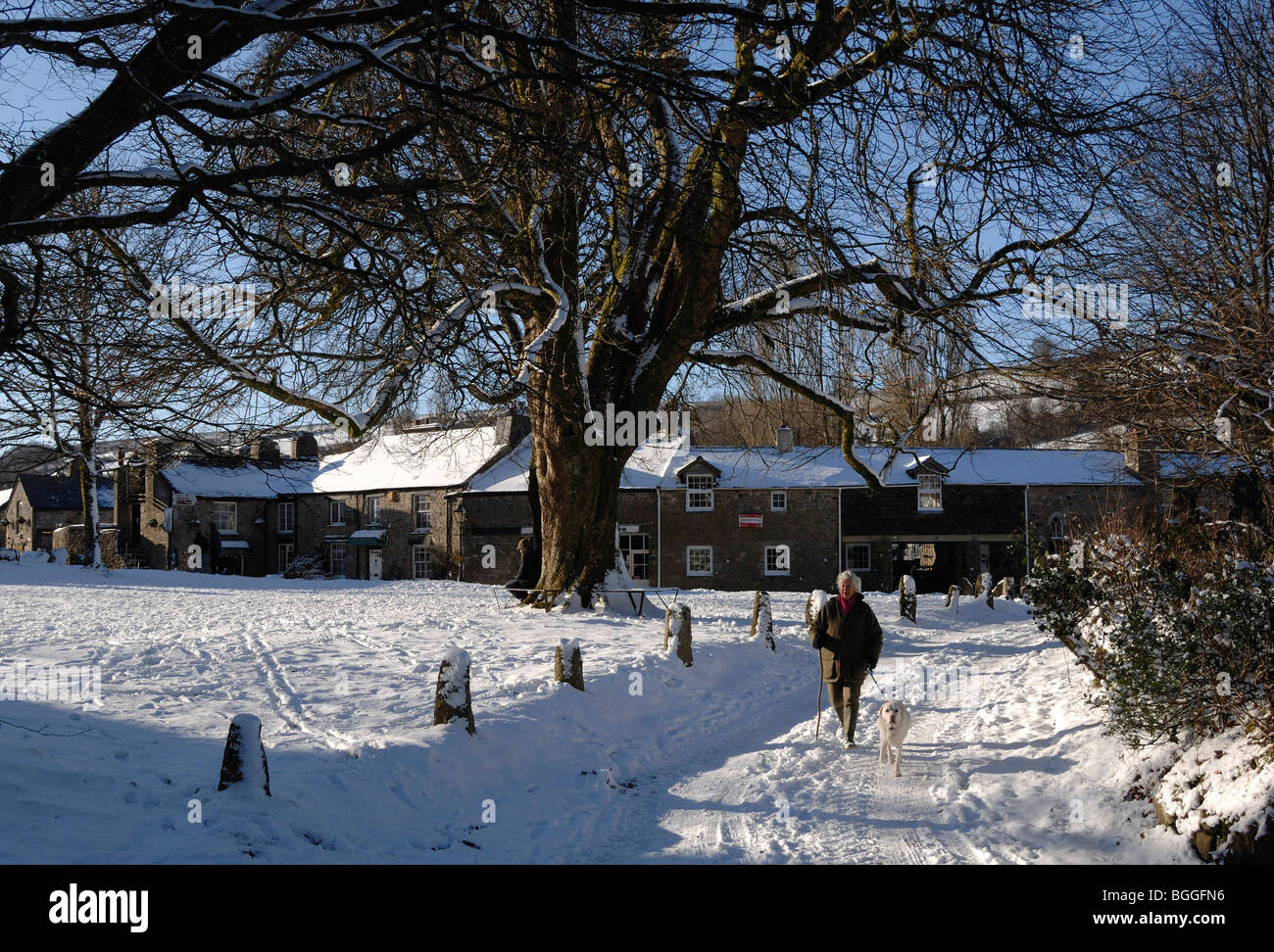 Femme marche un chien dans la neige dans Widecome dans le Dartmoor National Park village Maure Devon, Angleterre Banque D'Images