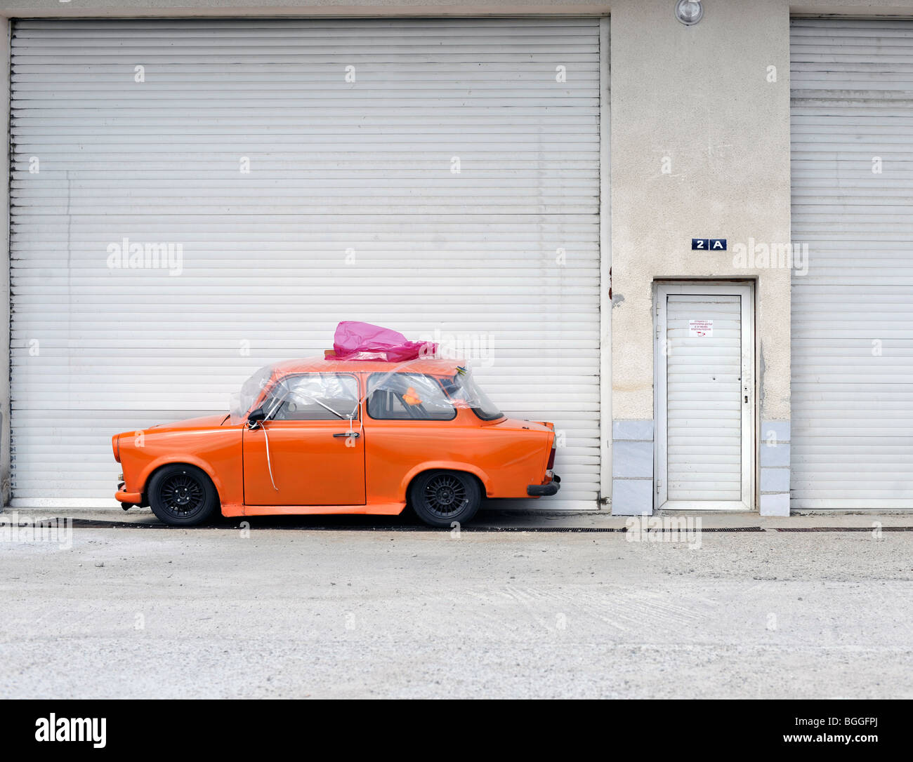 Orange voiture garée en face de portes de garage Banque D'Images