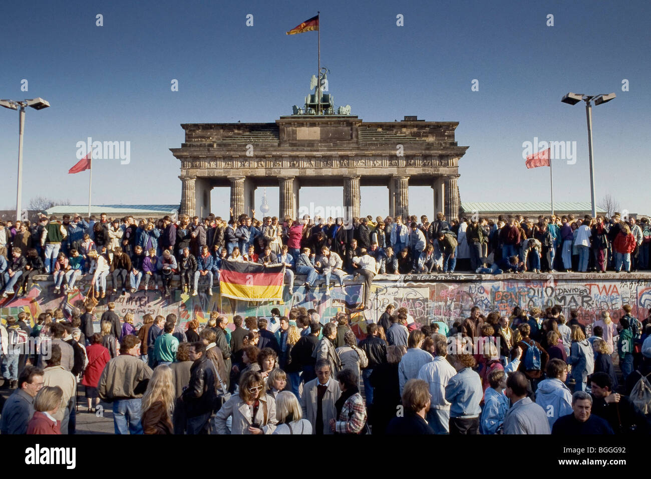 Chute du Mur de Berlin : les gens de l'Est et l'ouest de l'escalade sur le mur de Berlin à la porte de Brandebourg, Berlin, Allemagne Banque D'Images