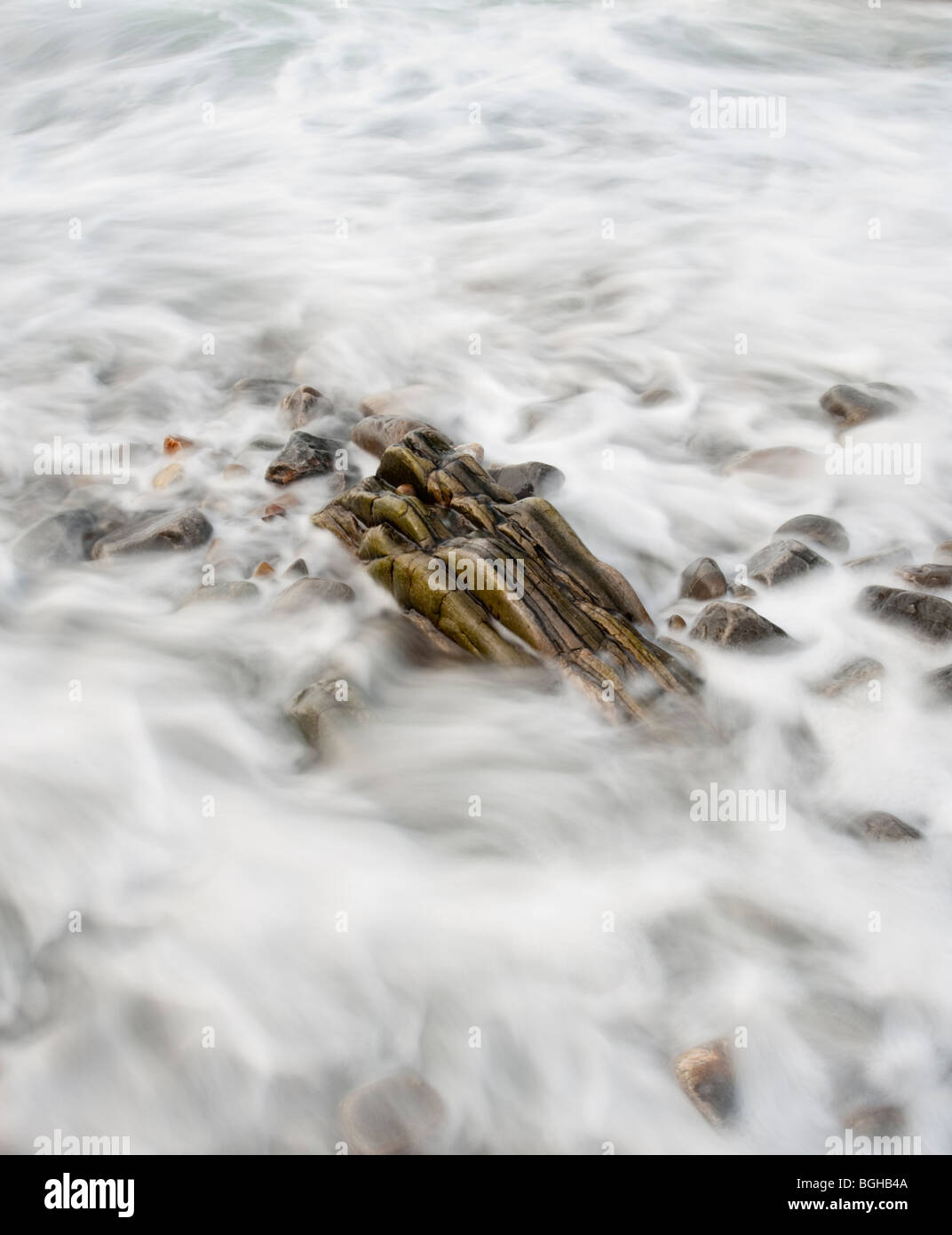 Belles images d'art créé par la longue exposition de vagues se déplacer au-dessus des cailloux et des rochers sur une plage au crépuscule écossais Banque D'Images