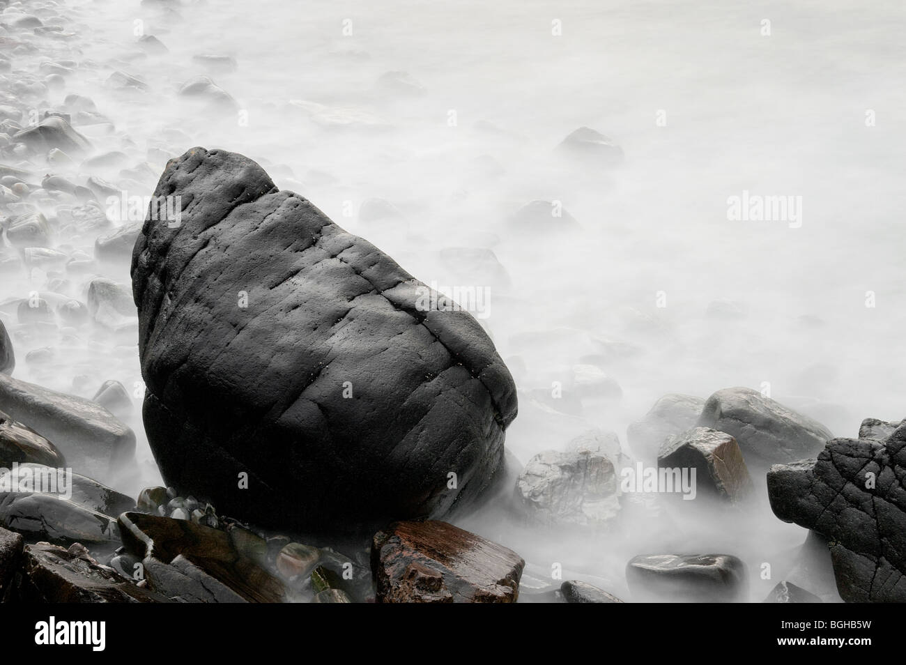 Belles images d'art créé par une longue exposition de vagues déménagement autour d'un énorme rocher et rochers sur une plage au crépuscule écossais Banque D'Images